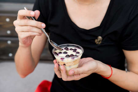 Woman eats dessert with blueberries in restaurantの写真素材