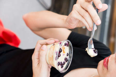 Woman eats dessert with blueberries in restaurantの写真素材