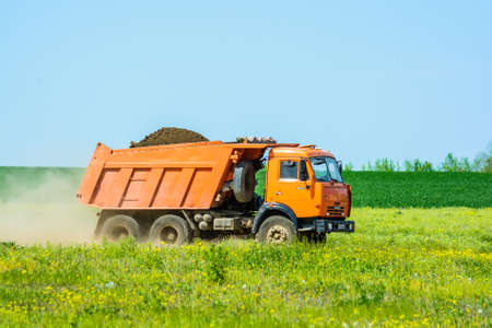 Orange truck with soil in fieldの写真素材
