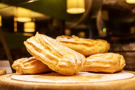 Close up delicious fresh eclair cakes with custard on wooden boardの写真素材