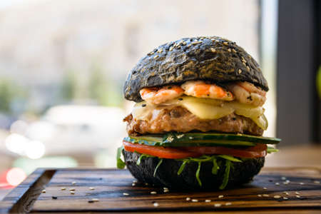 Black burger with prawns on wooden boardの写真素材