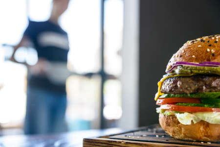 Fresh burger on board and blurred figure of personの写真素材