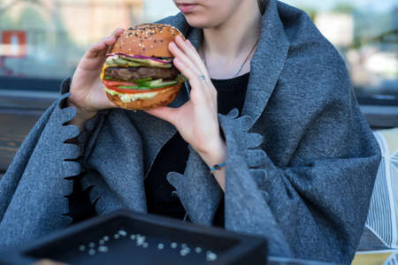 Young beautiful woman eats burger in restaurantの写真素材