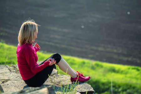 Back view young beautiful woman sits on rockの写真素材