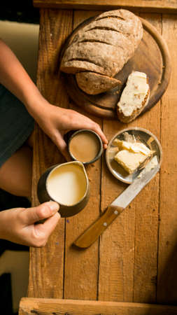 Top view woman has breakfast adds milk to coffee