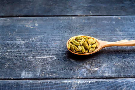 Cardamom seeds in wooden spoon dark backgroundの写真素材