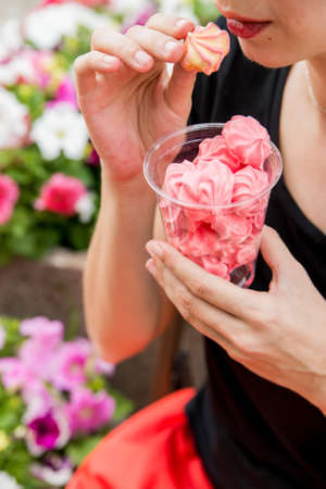 Young woman eats pink meringues outdoorsの写真素材