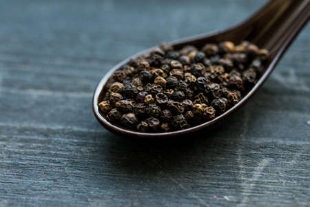 Close up black peppercorn in spoon dark backgroundの写真素材