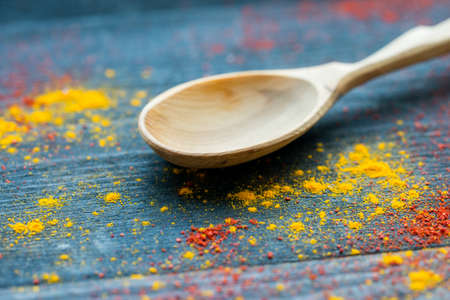 Empty wooden spoon on table covered in spicesの写真素材
