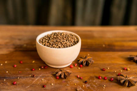 Coriander seeds in bowl on wooden table and spicesの写真素材