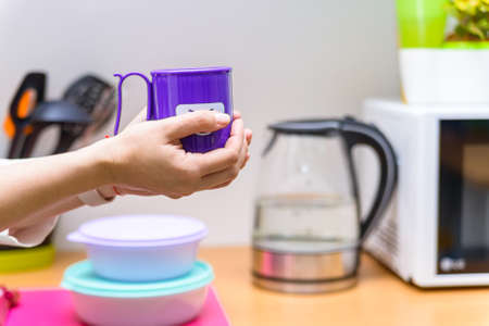 Hands hold plastic cup with smiling face
