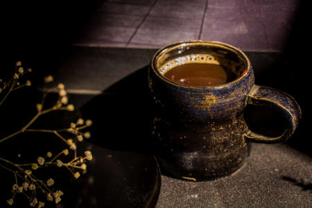 Dark still life vintage coffee mug and dry branchの写真素材