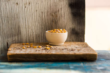 Corn grain in wooden bowl on wooden trayの写真素材