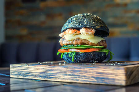 Black burger with prawns on wooden boardの写真素材
