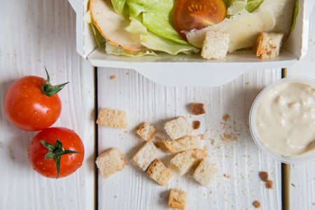 Caesar salad in box on white wooden surfaceの写真素材