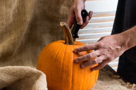 Male hands carving pumpkinの写真素材