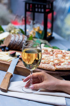 Female hand with glass of wine,pizza in backgroundの写真素材