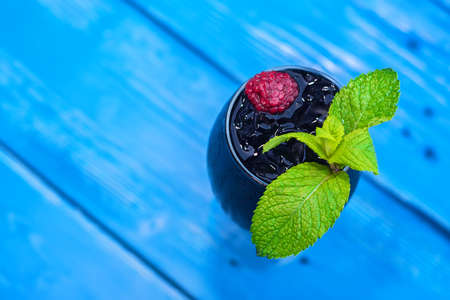 Dark restaurant cocktail with mint and raspberry