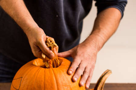 Male hands carving pumpkin taking out seedsの写真素材