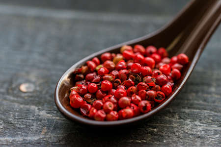 Studio shot of spoon filled with pink peppercorn on dark backgroundの写真素材