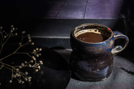 Dark still life vintage coffee mug and dry branchの写真素材
