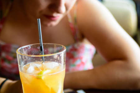 Woman drinks orange cocktail in cafeの写真素材