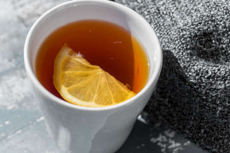 Close up white cup of lemon tea wrapped in blanketの写真素材