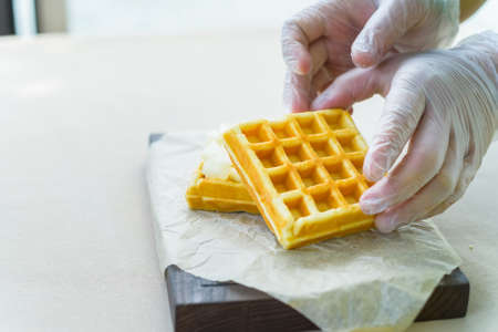 Hands in gloves put belgian waffles on trayの写真素材