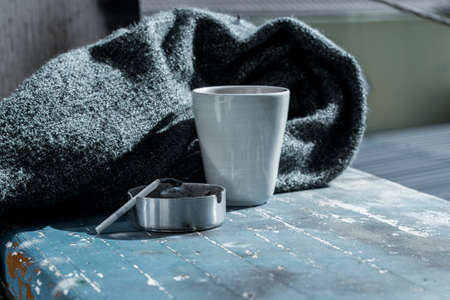 Teacup, blanket and ashtray grey fall background