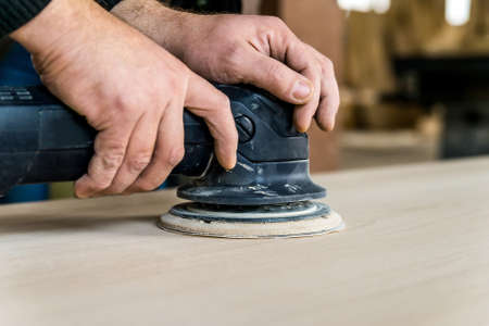 Close up man sanding wood in workshopの写真素材