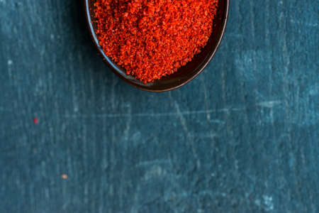 Close up spoon filled with red paprika spice on dark wooden backgroundの写真素材