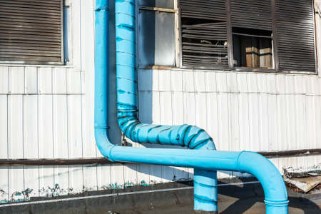 Close up wall of factory building and blue metal pipesの写真素材