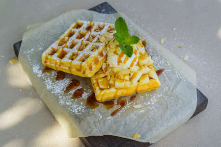 Close up delicious belgian waffles with ice cream, syrup and nuts on napkinの写真素材