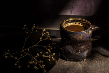 Dark still life vintage coffee mug and dry branchの写真素材