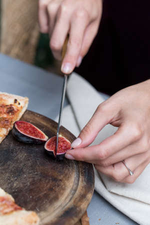 Close up female hands cutting fig with knifeの写真素材