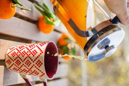 Pouring tangerine tea into cup on wooden tableの写真素材