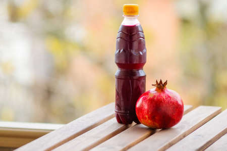 Pomegranate and bottle of juice on wooden tableの写真素材