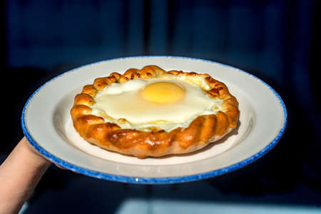 Close up woman holds plate with khachapuriの写真素材