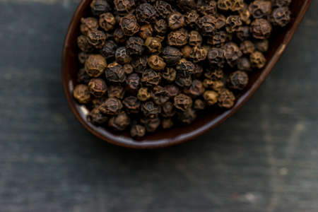 Close up black peppercorn in spoon dark background