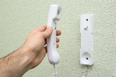 Hand holds handset of entry phone
