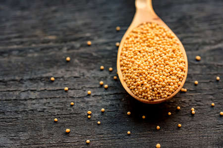 Mustard seeds in wooden spoon close upの写真素材
