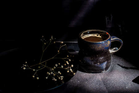 Dark still life vintage coffee mug and dry branchの写真素材