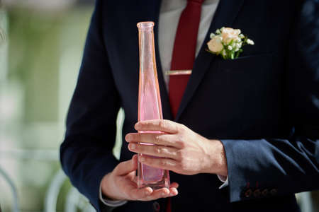 Groom holds bottle with pink sand at weddingの写真素材