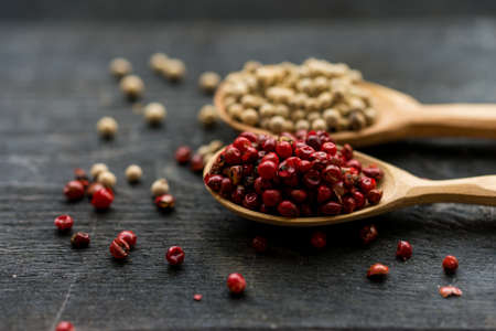 Close up studio shot of pink and white peppercorn in wooden spoons on dark backgroundの写真素材