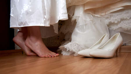 Close up feet of bride standing on tiptoes and white wedding shoes
