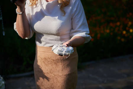 Close up woman's hand holding white pillow with two wedding rings outdoorsの写真素材
