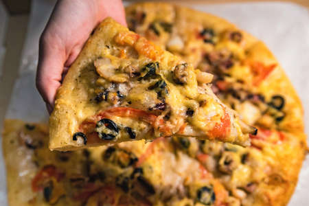 Top view hand holds slice of pizza