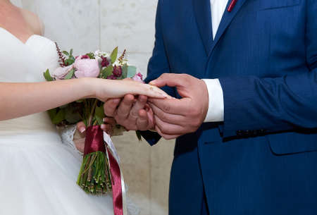Close up hands of newlywed couple exchanging wedding rings