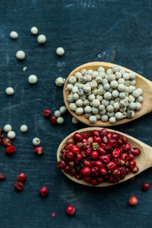 Two wooden spoons with pink and white peppercornの写真素材
