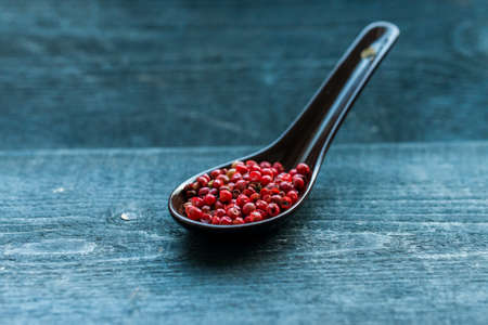 Close up pink peppercorn in spoon dark backgroundの写真素材
